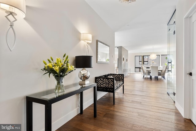 corridor with a chandelier and light hardwood / wood-style floors