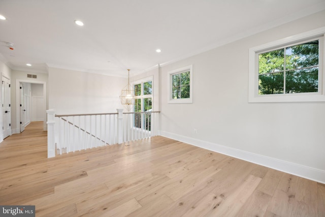 empty room featuring crown molding, light hardwood / wood-style floors, and a notable chandelier