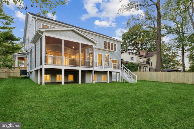 rear view of house featuring a wooden deck, a yard, and a sunroom