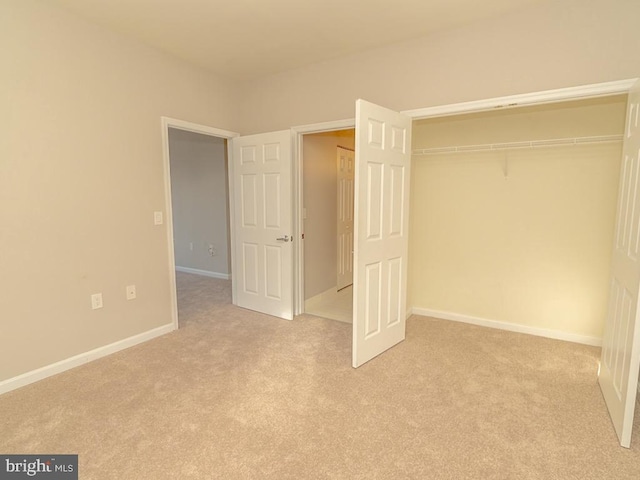 unfurnished bedroom with light carpet and a closet