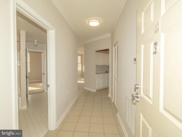 corridor featuring ornamental molding and light tile floors