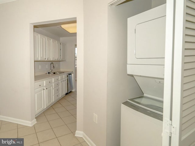 laundry room featuring light tile floors, stacked washer / dryer, and sink