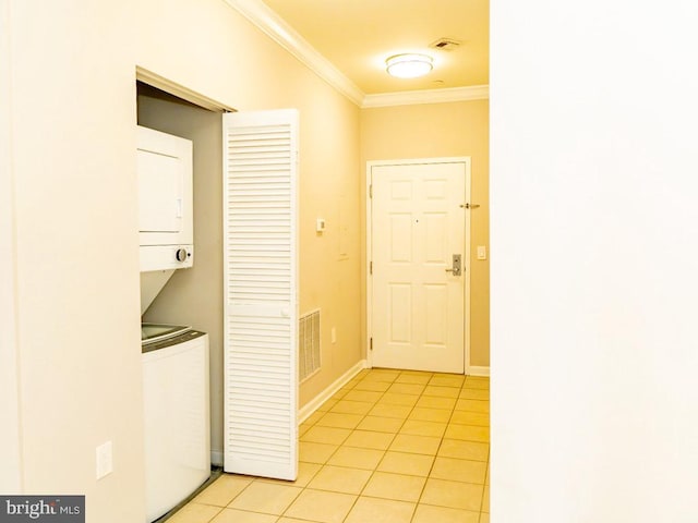 corridor featuring light tile floors, crown molding, and stacked washer / dryer