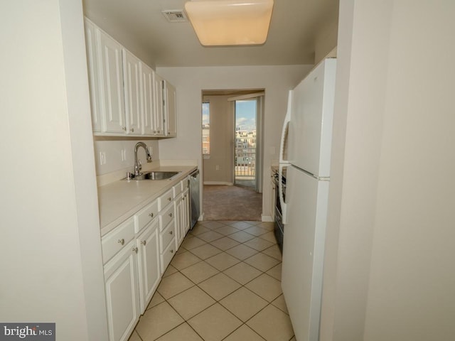 kitchen featuring light tile flooring, stainless steel dishwasher, white fridge, sink, and white cabinetry