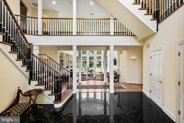 tiled entryway featuring decorative columns and a high ceiling