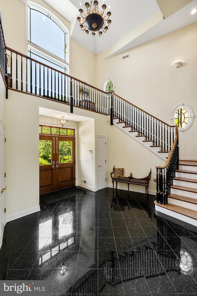 tiled entrance foyer featuring a notable chandelier and a high ceiling