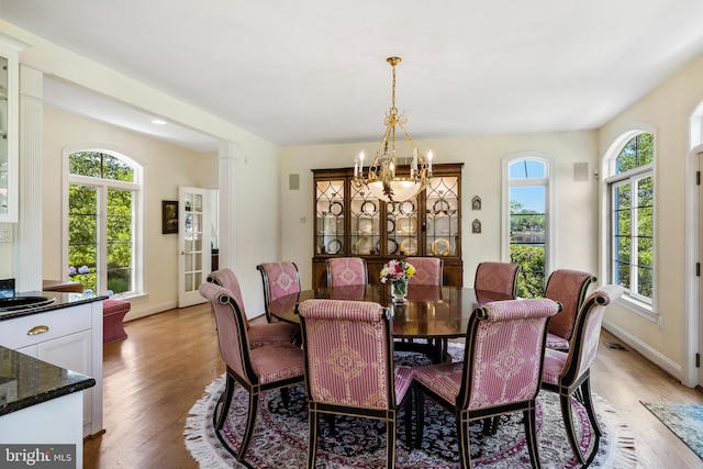 dining space featuring a notable chandelier, a wealth of natural light, and light wood-type flooring