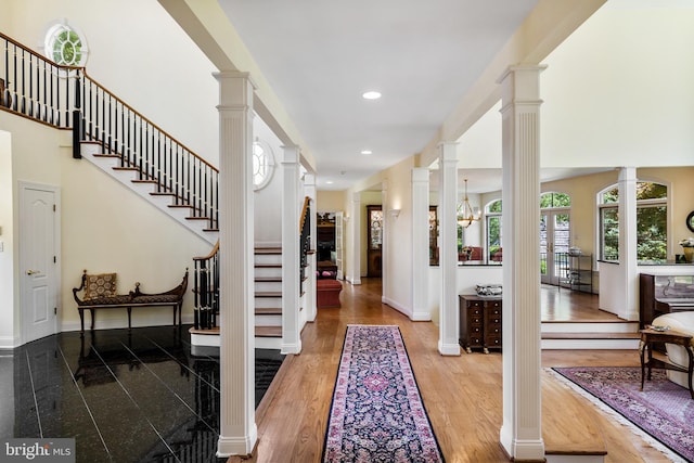 entryway with a notable chandelier, plenty of natural light, light hardwood / wood-style flooring, and ornate columns