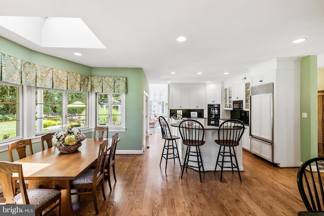 dining space featuring a skylight and light wood-type flooring