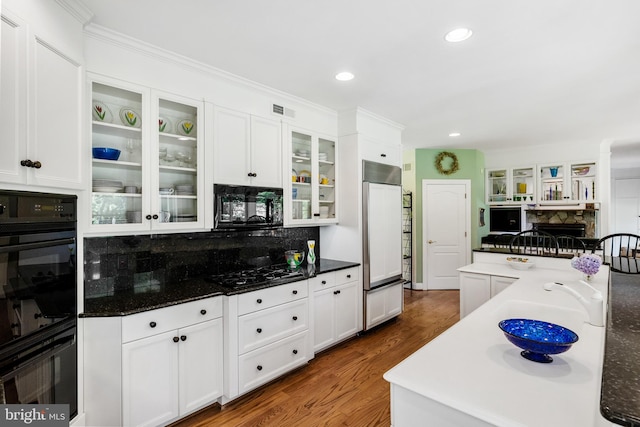 kitchen featuring dark hardwood / wood-style flooring, a fireplace, black appliances, and white cabinets