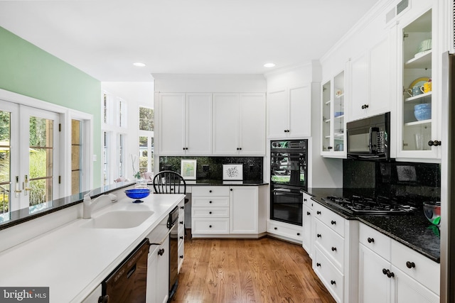 kitchen featuring backsplash, white cabinetry, sink, and black appliances