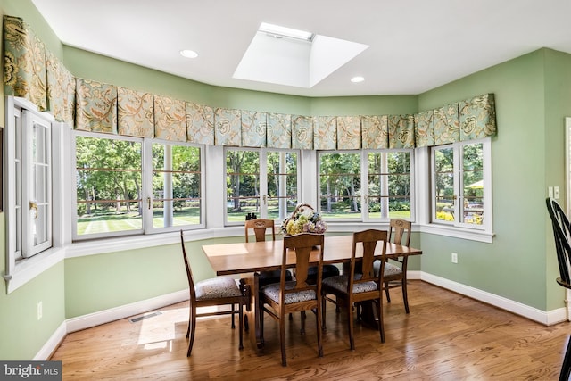 dining area featuring a skylight and light hardwood / wood-style floors