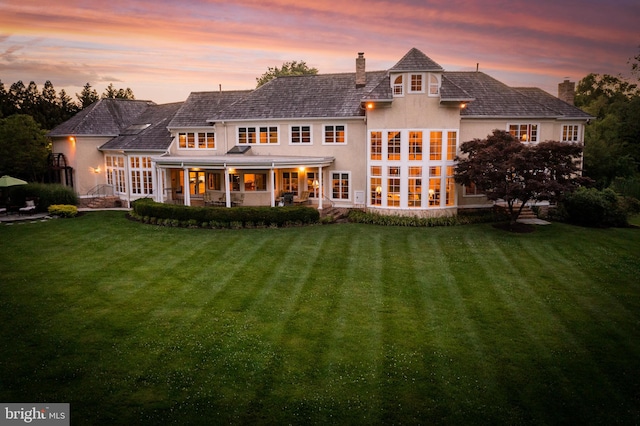 back house at dusk with a lawn