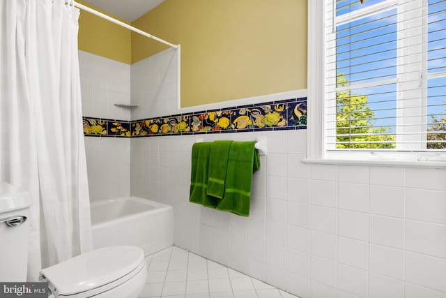 bathroom featuring tile flooring, shower / bathtub combination with curtain, toilet, and tile walls