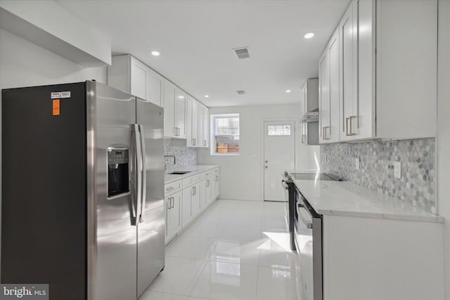 kitchen featuring white cabinetry, backsplash, light tile flooring, light stone counters, and stainless steel refrigerator with ice dispenser