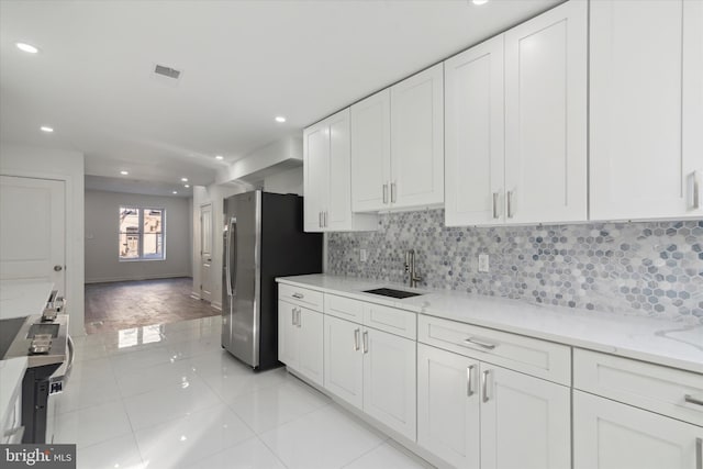 kitchen featuring tasteful backsplash, white cabinetry, light tile floors, and sink