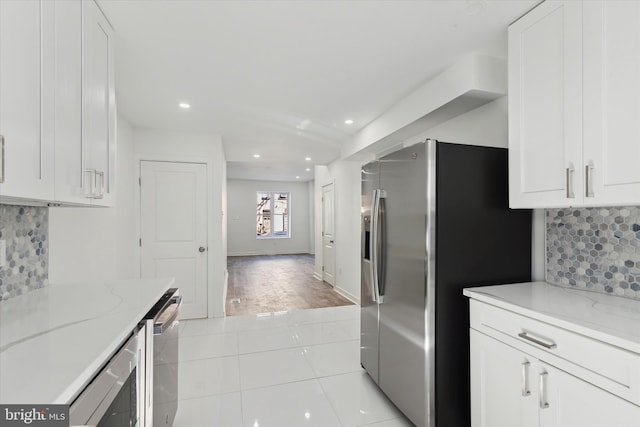 kitchen featuring backsplash, light tile flooring, and white cabinets