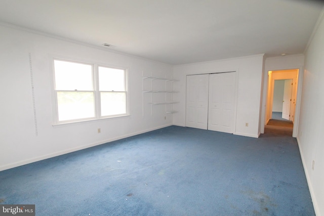 unfurnished bedroom with a closet, ornamental molding, and dark colored carpet