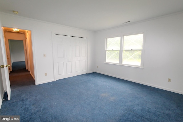 unfurnished bedroom with crown molding, a closet, and dark colored carpet