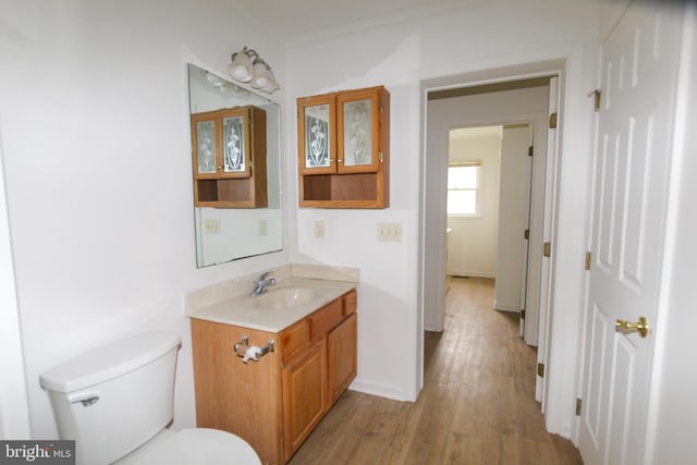 bathroom with hardwood / wood-style flooring, vanity, toilet, and ornamental molding