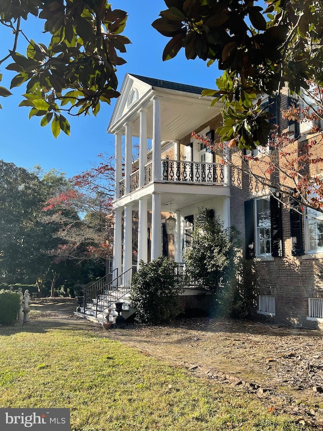 view of front of house with a front lawn and a balcony