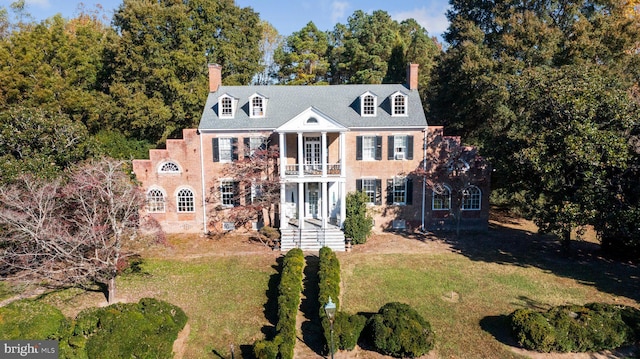 view of front facade with a front yard, french doors, and a balcony