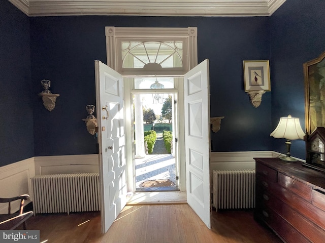 entryway with radiator, ornamental molding, and wood-type flooring