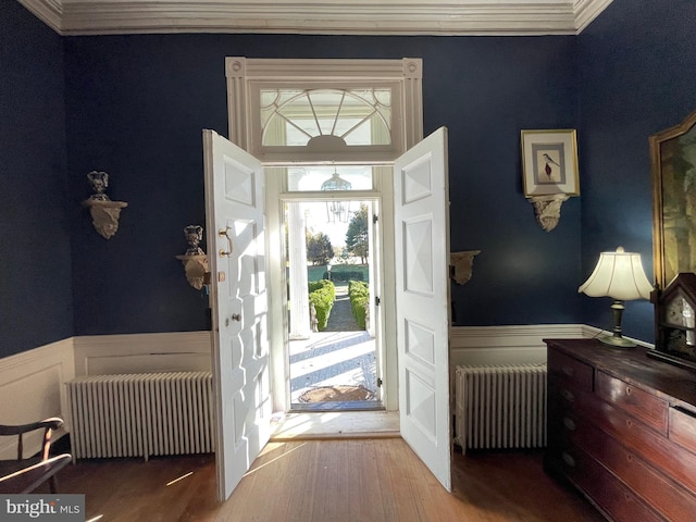 entrance foyer with hardwood / wood-style floors, crown molding, and radiator heating unit