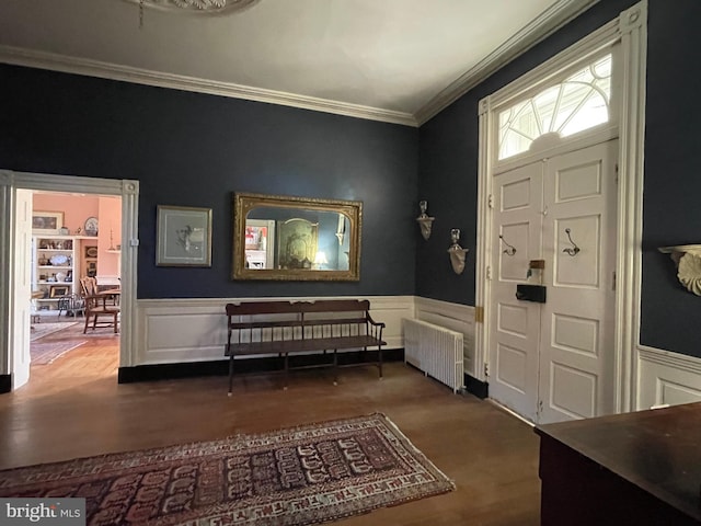 foyer with radiator heating unit, wood-type flooring, and crown molding