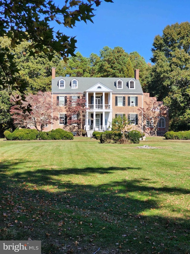 view of front facade featuring a balcony and a front yard