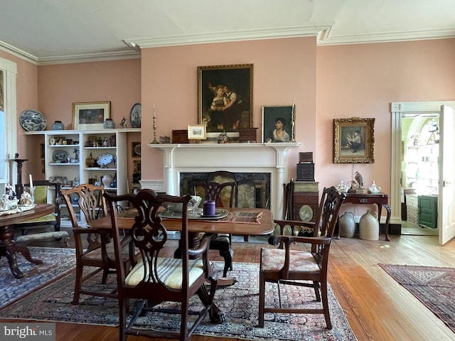 dining space with hardwood / wood-style flooring, a healthy amount of sunlight, and ornamental molding