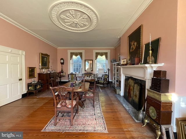 dining area featuring crown molding, a fireplace, and hardwood / wood-style floors