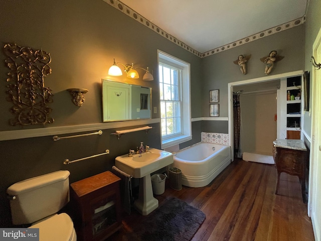 bathroom with sink, toilet, hardwood / wood-style floors, and a washtub