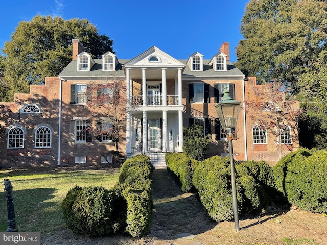 view of front of house featuring a front lawn and a balcony