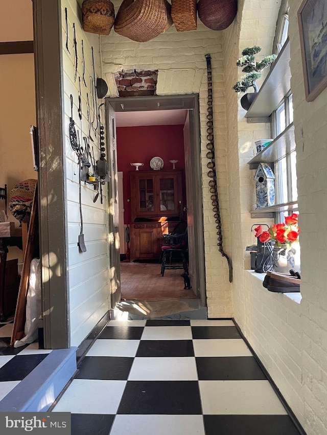 corridor featuring brick wall and tile patterned floors