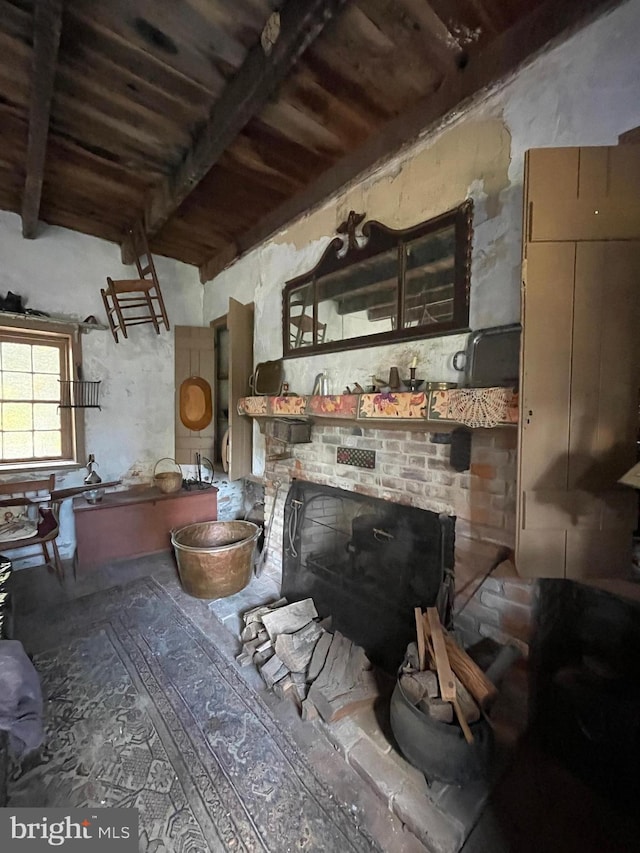 misc room featuring beam ceiling and a brick fireplace