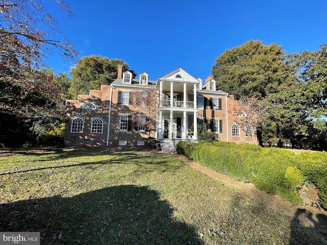 rear view of house with a balcony and a lawn