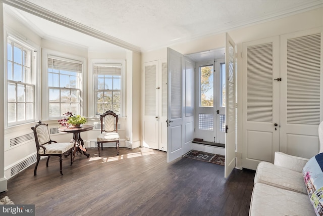 interior space with a textured ceiling, dark hardwood / wood-style floors, and crown molding