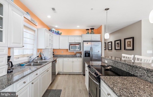 kitchen featuring sink, dark stone counters, white cabinets, light hardwood / wood-style flooring, and stainless steel appliances