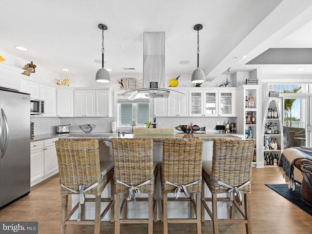 kitchen with island range hood, a healthy amount of sunlight, appliances with stainless steel finishes, and a kitchen bar