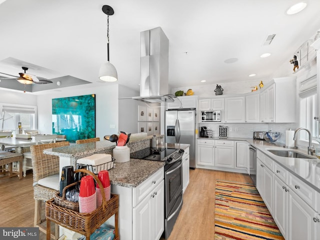 kitchen with appliances with stainless steel finishes, ceiling fan, sink, white cabinetry, and island range hood