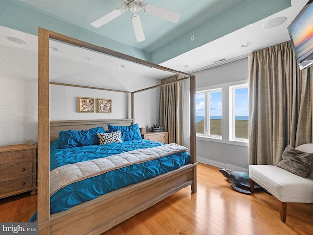 bedroom with a water view, ceiling fan, and light wood-type flooring