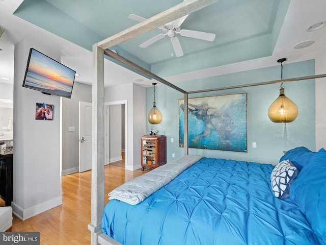 bedroom with a raised ceiling, light hardwood / wood-style floors, and ceiling fan