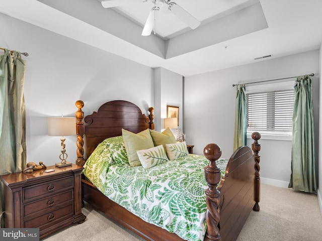 carpeted bedroom featuring a raised ceiling and ceiling fan