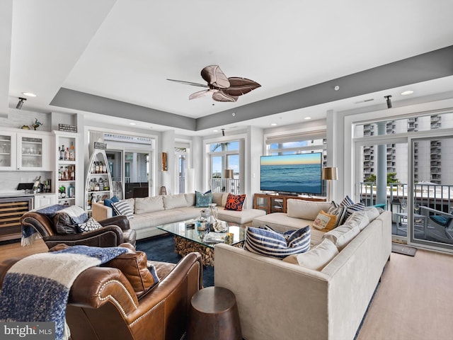 living room with ceiling fan, wine cooler, light hardwood / wood-style flooring, and a healthy amount of sunlight