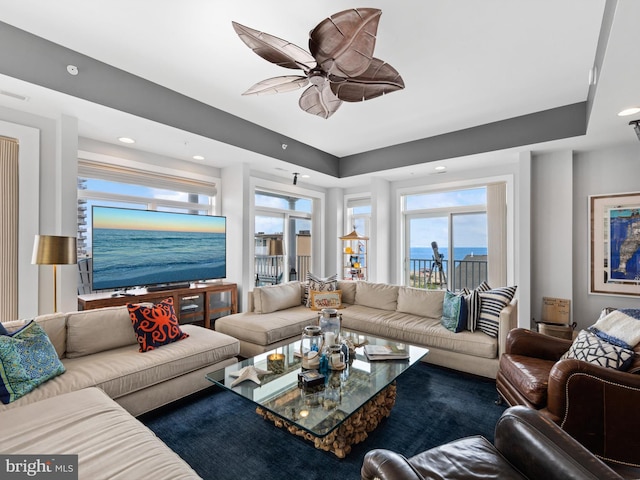 living room featuring ceiling fan and a water view