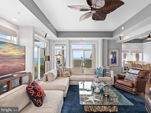 living room with a raised ceiling and ceiling fan