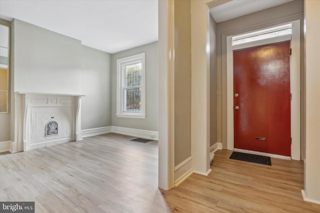 entryway with light wood finished floors, visible vents, and baseboards