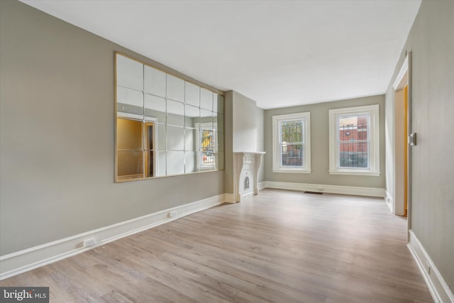 spare room featuring a fireplace, wood finished floors, visible vents, and baseboards