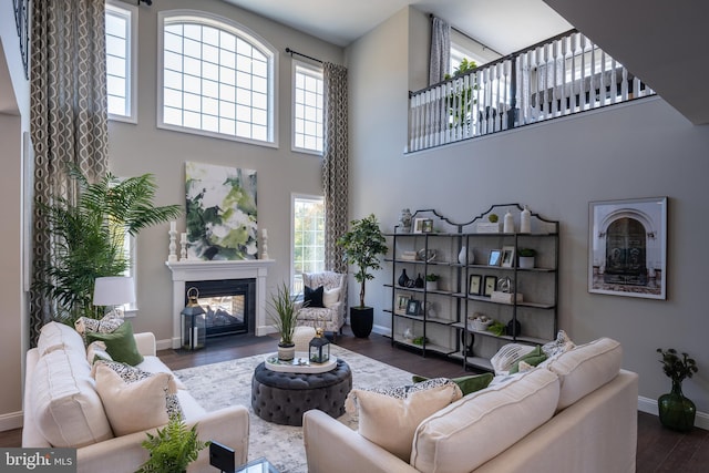 living area with a glass covered fireplace, plenty of natural light, wood finished floors, and baseboards